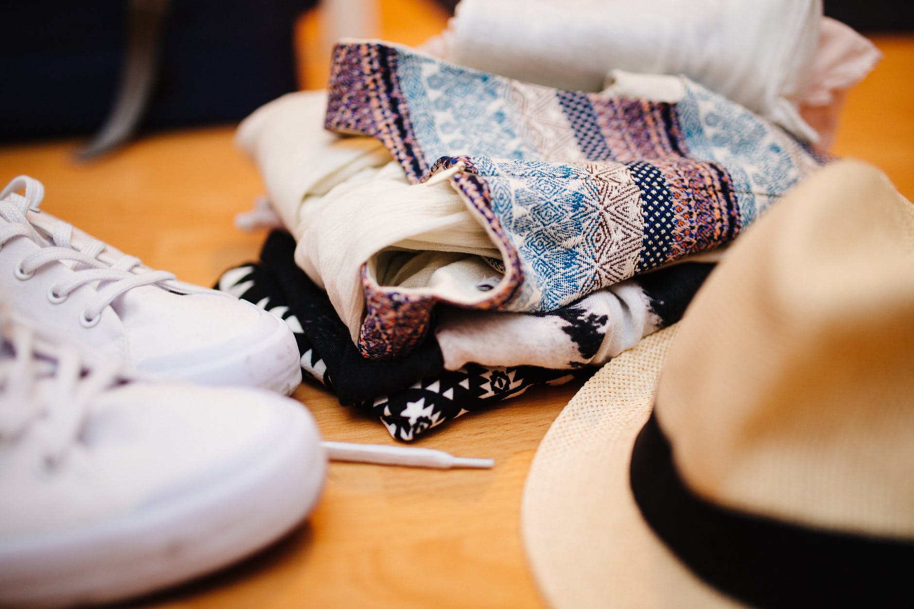 brown fedora hat beside white sneakers and blue textile